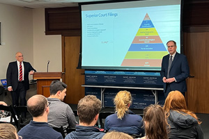Judge Temple and Attorney Iacopino speak to attendees at Saint Anselm College in front of pyramid shaped diagram