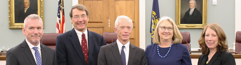 Five supreme court justices standing next to each other in a courtroom.